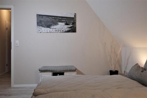 a white bedroom with a bed and a stool at FEWO Ostseeland in Grömitz