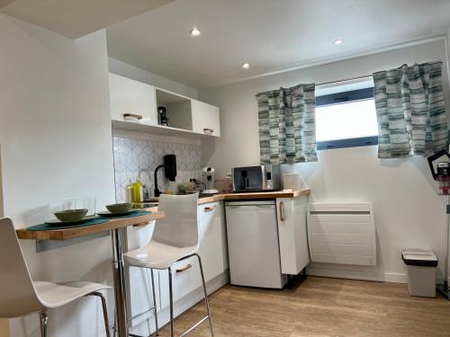 - une cuisine avec des appareils blancs, une table et des chaises dans l'établissement Charmant studio totalement neuf Beaumont, à Beaumont
