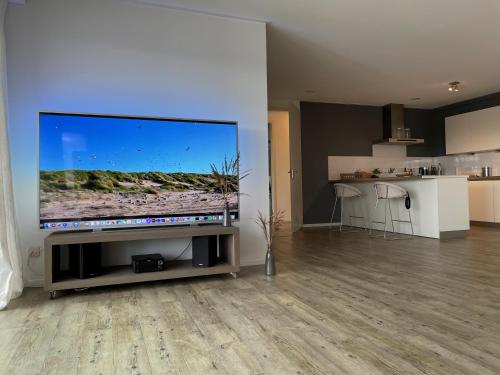 a living room with a large flat screen tv on a wall at Näher am Wasser kann man nicht wohnen! in Arnemuiden