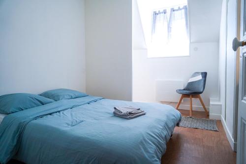 - une chambre avec un lit doté de draps bleus et d'une chaise dans l'établissement L'Ilot Secret - Fibre - Proche gare, à Châteauroux
