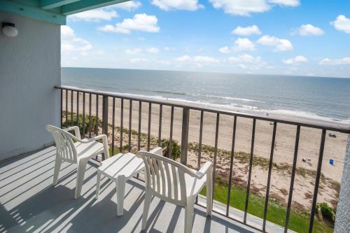 two chairs and a table on a balcony overlooking the beach at Tropical Seas Hotel in Myrtle Beach
