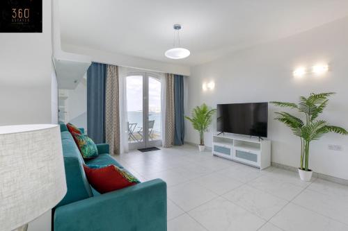 uma sala de estar com um sofá azul e uma televisão em Seafront, Studio home with Private Seaview terrace by 360 Estates em St. Paul's Bay
