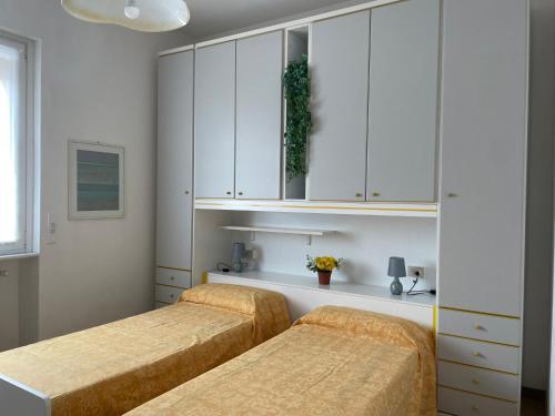 two beds in a bedroom with white cabinets at Il nido del merlo Parcheggio e giardino in Verbania