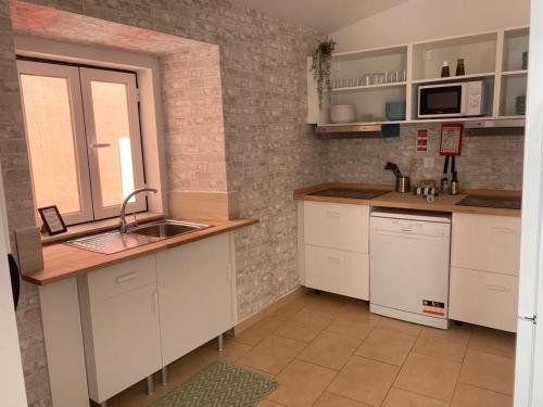 una cocina con armarios blancos y fregadero en 5 Senses Hostel en Setúbal