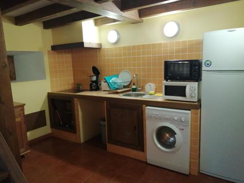 a kitchen with a white refrigerator and a washing machine at Caballito de Madera in Pelegrina