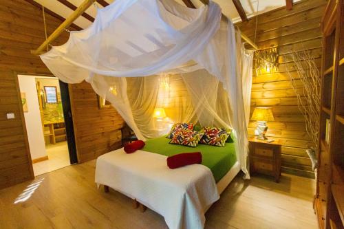 a bedroom with a bed with a canopy at Gîtes Atemoya. Petit Bas Vent Fort Royal. in Deshaies