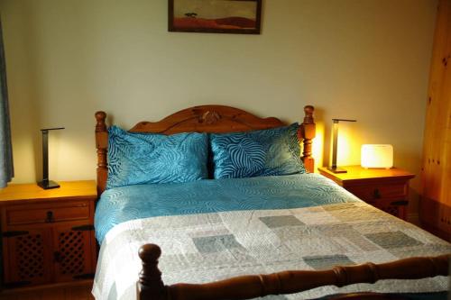 a bedroom with a bed with blue pillows and two lamps at Cosy & convenient beach retreat in Tramore