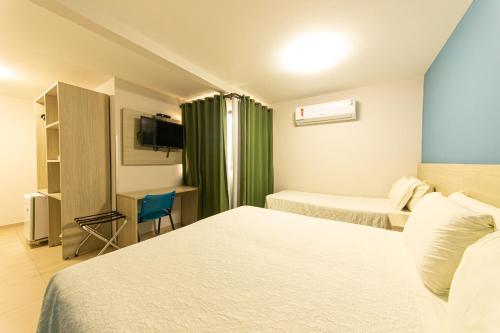 a hotel room with two beds and a desk at Pousada Mariluz in Maragogi