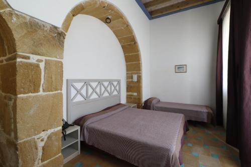 1 dormitorio con cama y pared de piedra en Hotel Villa Fanusa, en Siracusa