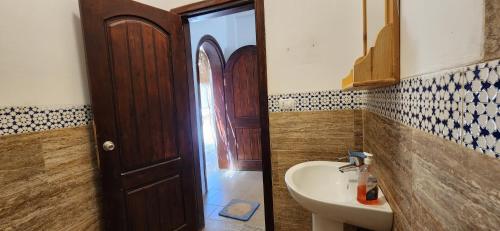 baño con lavabo, espejo y puerta en Rayhana Guest House, en Marsa Alam