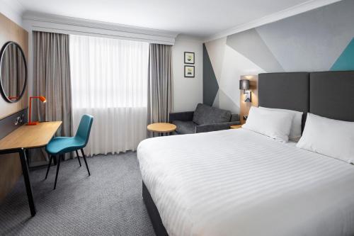 a hotel room with a bed and a chair at Holiday Inn Gloucester - Cheltenham, an IHG Hotel in Gloucester