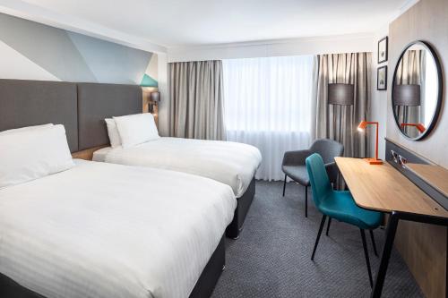 a hotel room with two beds and a desk at Holiday Inn Gloucester - Cheltenham by IHG in Gloucester