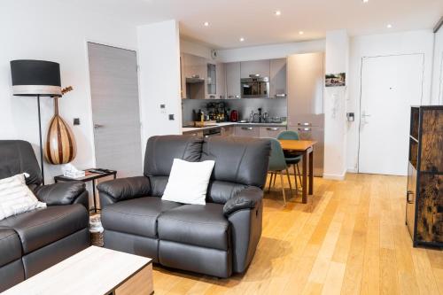 un salon avec un canapé en cuir et une table dans l'établissement Convenient 2BR Apt near subway, à Noisy-le-Grand