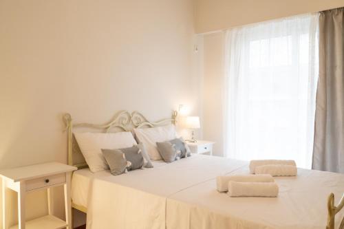 a white bedroom with a large bed with two pillows at AMALTHIA PIRAEUS in Piraeus
