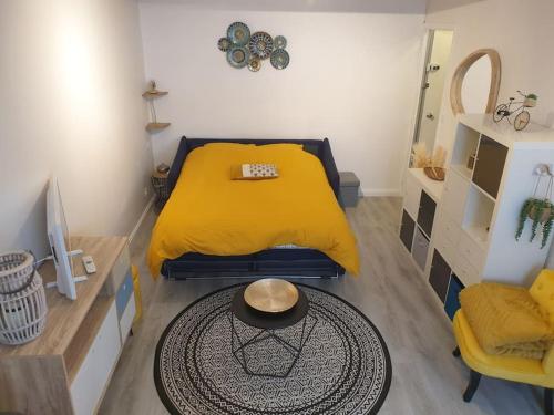 - une petite chambre avec un lit jaune et une table dans l'établissement Charmant studio avec place de parking, à Nancy