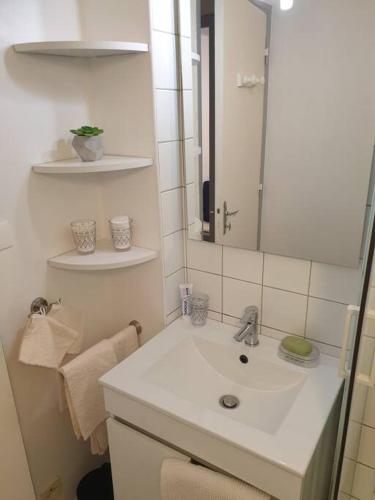 une salle de bain blanche avec un lavabo et un miroir dans l'établissement Charmant studio avec place de parking, à Nancy