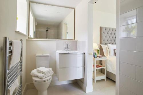 a bathroom with a toilet and a sink and a bed at The Garden House - Luxurious bolthole near coast in Banningham