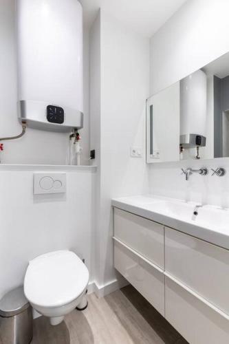 une salle de bain blanche avec des toilettes et un lavabo dans l'établissement Gaité Montparnasse : Magnifique Studio, à Paris
