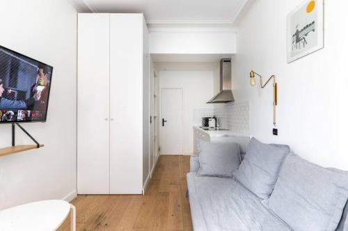 un salon blanc avec un canapé et une télévision dans l'établissement Gaité Montparnasse : Magnifique Studio, à Paris