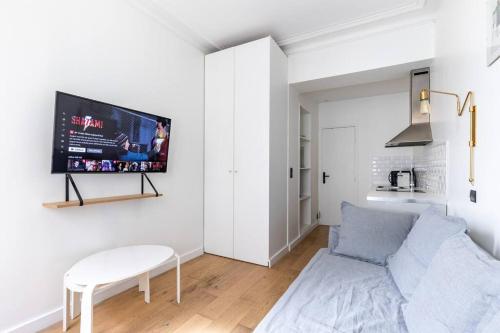un salon avec un canapé et une télévision sur un mur dans l'établissement Gaité Montparnasse : Magnifique Studio, à Paris