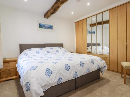 a bedroom with a bed with a white and blue comforter at Harvenna Cottage in Bude