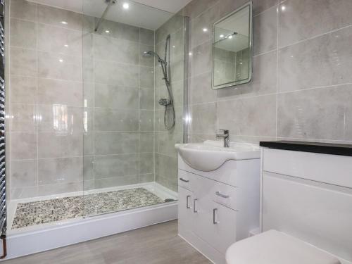 a bathroom with a shower and a toilet and a sink at Harvenna Cottage in Bude