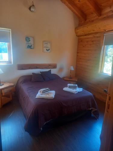 1 dormitorio con 1 cama con 2 toallas en Cabañas Peumayen Meliquina en Villa Meliquina