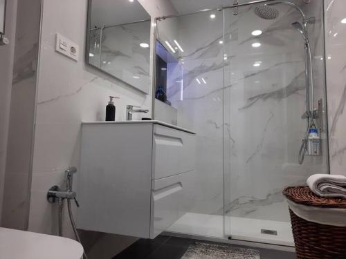a white bathroom with a shower and a sink at Soleado apartamento con garaje in Santander