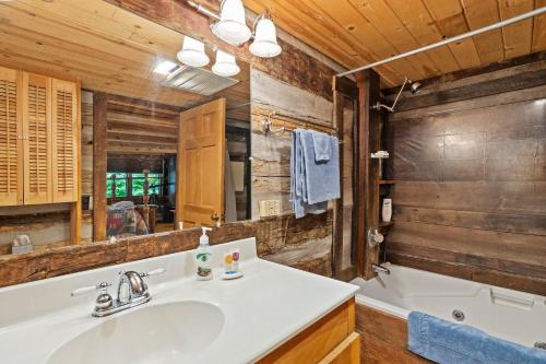 a bathroom with a sink and a tub and a mirror at Logs Of Luxury Cabin - Golfers Dream in Swiss