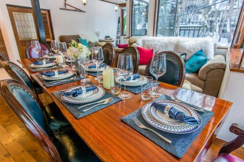 a wooden table with plates and wine glasses on it at Chalet Hakuba in Hakuba