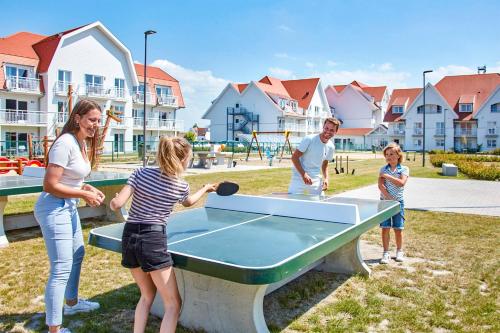 a family playing ping pong at a ping pong table at Holiday Suites Nieuwpoort in Nieuwpoort