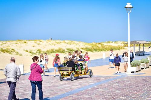 a group of people walking on the beach with a cart at Holiday Suites Nieuwpoort in Nieuwpoort