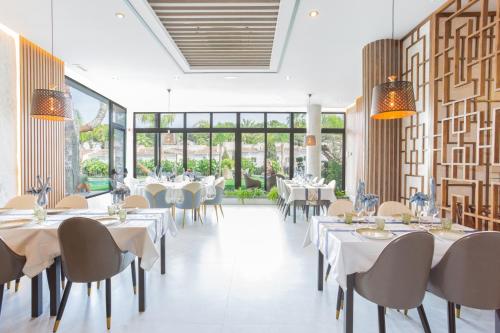 ein Restaurant mit weißen Tischen und Stühlen und großen Fenstern in der Unterkunft Hotel Casa Lili in Jávea