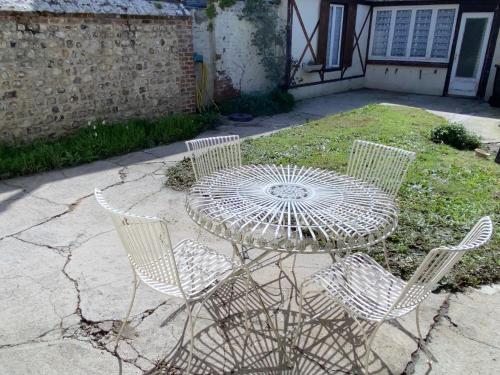 een tafel en drie stoelen en een tafel en stoelen bij Maison avec jardin et parking, au centre d'Etretat in Étretat