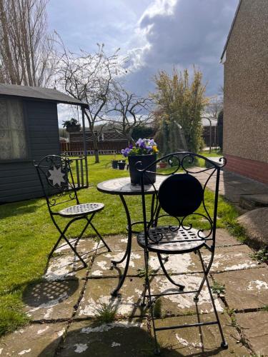 Dos sillas y una mesa con un jarrón. en Prelude Guesthouse, Brigsley Grimsby, en Grimsby