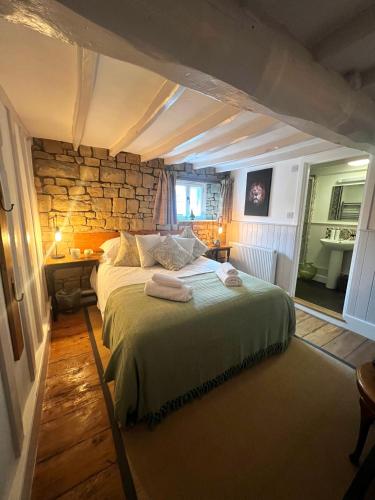 a bedroom with a large bed with a stone wall at The Lion, Tredington in Shipston on Stour