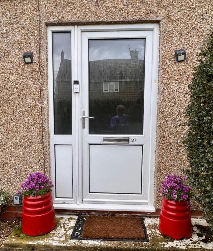 a white door with two red barrels in front of it at Prelude Guesthouse, Brigsley Grimsby in Grimsby