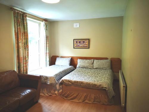 a bedroom with a bed and a couch and a window at Ashton Beach House in Tramore