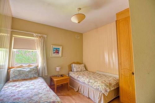 1 dormitorio con 2 camas y ventana en Ashton Beach House en Tramore