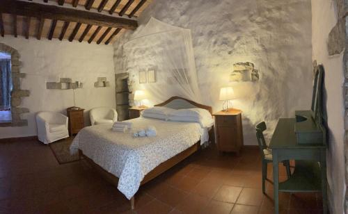 a bedroom with a bed with two chairs and a desk at Torre Di Ponzano in Barberino di Val dʼElsa