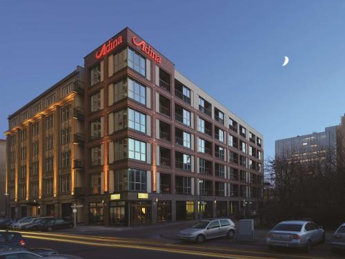 a building with cars parked in a parking lot at Adina Apartment Hotel Berlin Checkpoint Charlie in Berlin