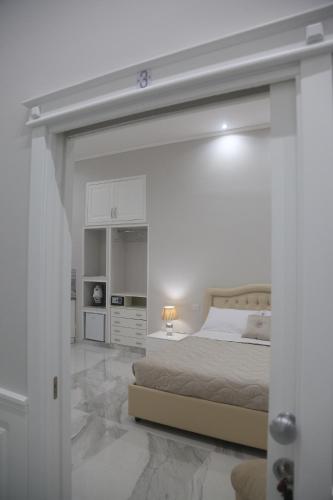 Dormitorio blanco con cama y pared blanca en Opera Home Napoli, en Nápoles
