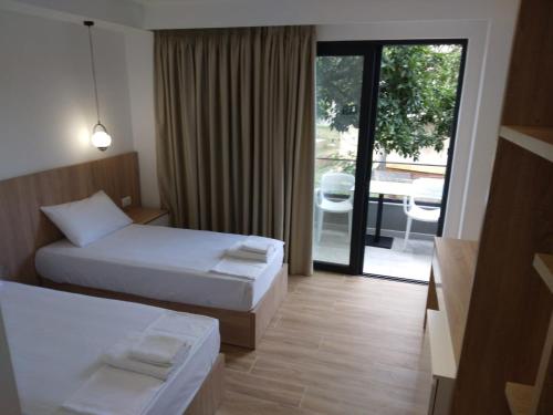 a hotel room with two beds and a sliding glass door at Hotel Ksamili in Ksamil