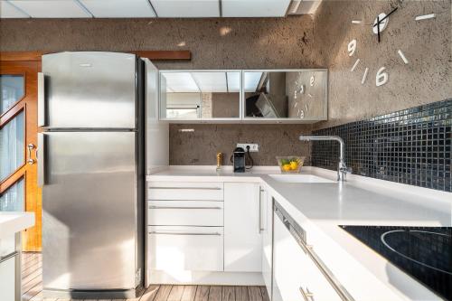 een keuken met witte kasten en een roestvrijstalen koelkast bij Villa Luxury Rock Tirri in Reus