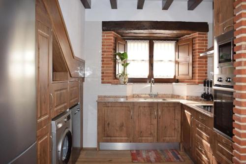 cocina con armarios de madera, fregadero y ventana en Casa Rural Los Riveros de Jeromo en Selaya