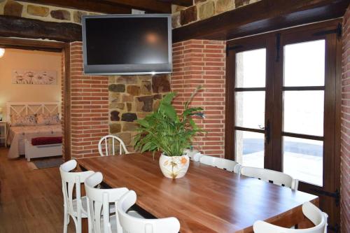 a dining room with a wooden table and white chairs at Casa Rural Los Riveros de Jeromo in Selaya