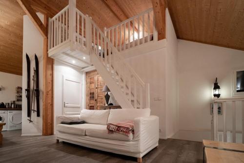 a living room with a white couch and stairs at L'ourse et L'ange - Luxury chalet (8p). 3 bedrooms, 2 bathrooms and a loft. In the centre of Vallandry, with ski-in & out in Landry