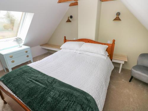 a bedroom with a bed and a chair and a window at Abaty Cottage in Haverfordwest