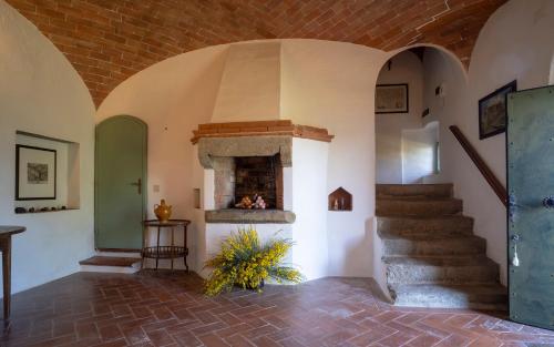 a room with a stone fireplace and a staircase at Castello del Calcione in Lucignano