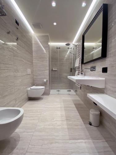 a bathroom with two sinks a toilet and a shower at Hotel Villa Letizia in Bardolino